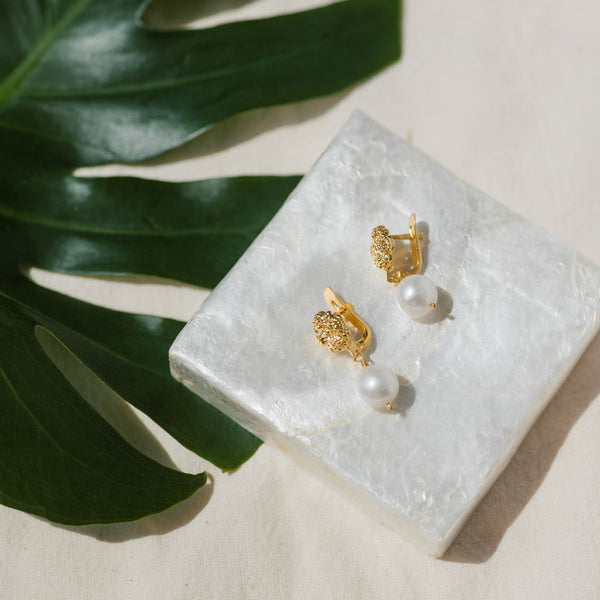 A pair of Philippine gold & pearl earrings set upon a capiz shell box.