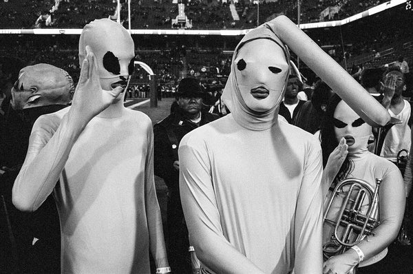 black and white photo of two people in masks at sporting event by Daniel Alvarez