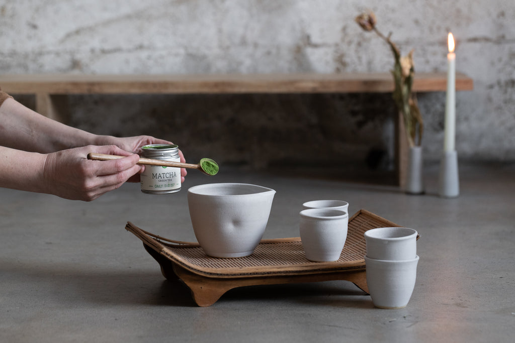 Person putting green tea powder into cup