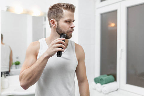 man trimming beard with beard trimmer