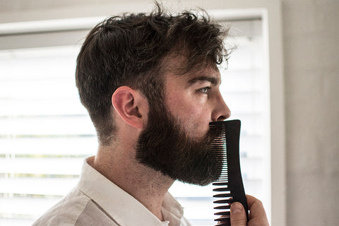 bearded man combing his beard
