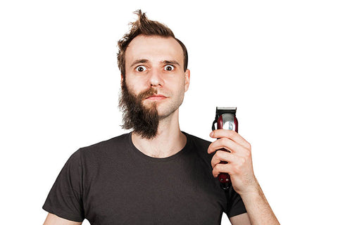 man using clipper to remove half of his beard