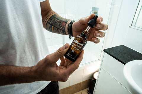 man holding king of wood beard oil in bathroom