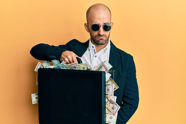 man with shaved head saving a suitcase of money