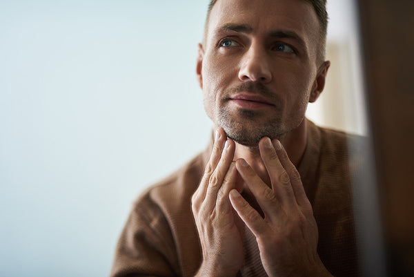 man caring for his stubble in the bathroom mirror