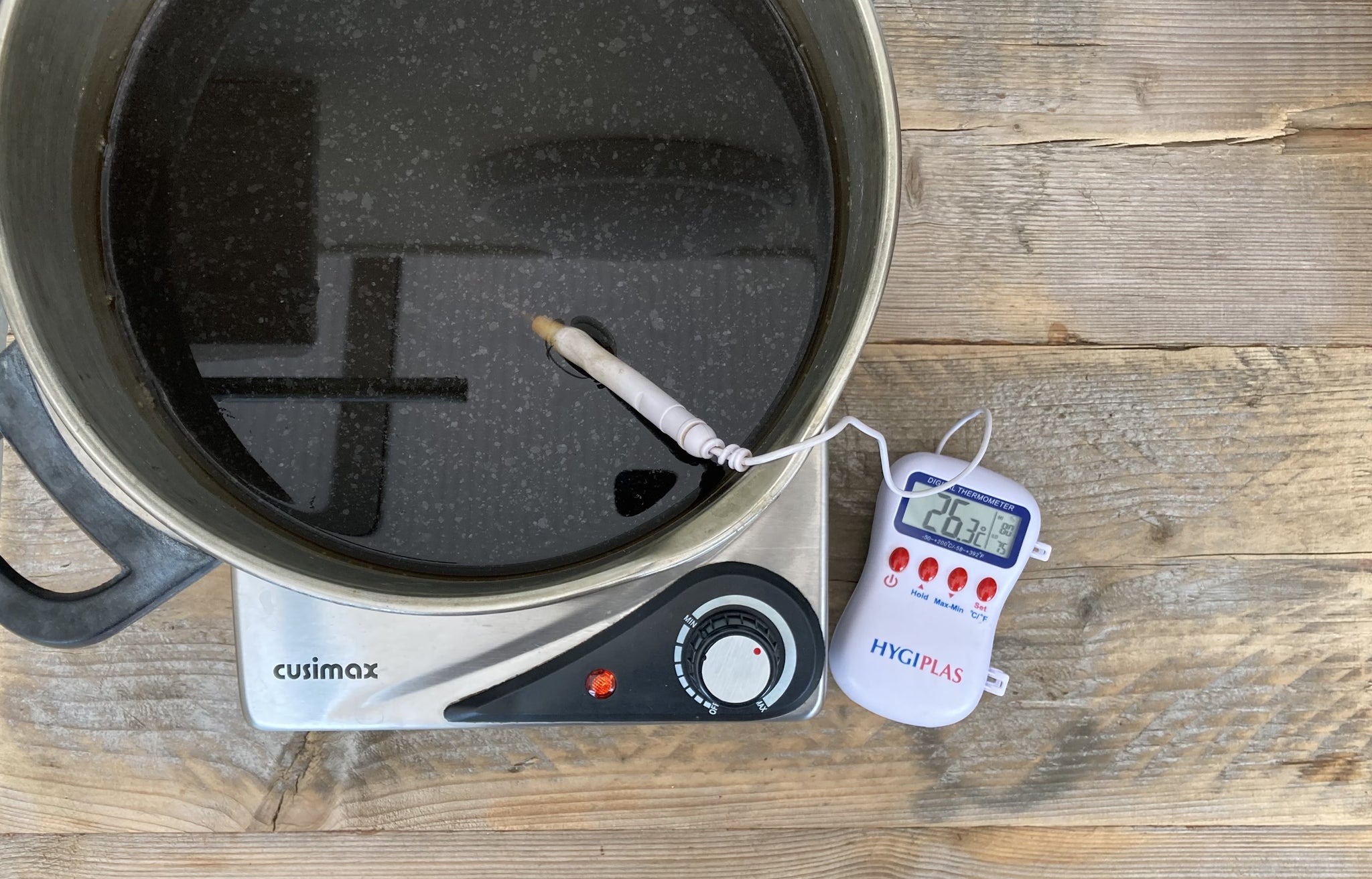 Heating the crushed acorns in the saucepan on a hob, checking the temperature with an electric thermometer