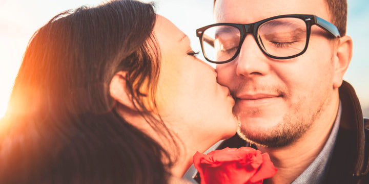 Valentines day date couple woman kissing man with black prescription glasses