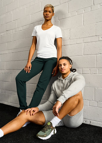 Tall man seated and tall woman standing, both wearing workout clothes