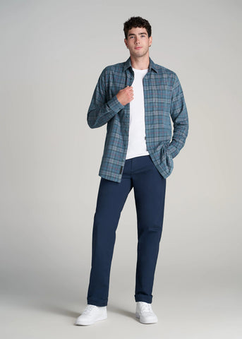 Man standing wearing plaid button corduroy overshirt undone over white tee and pants