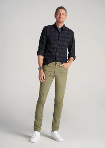 Tall man standing with one hand in pocket wearing twill pants and button shirt
