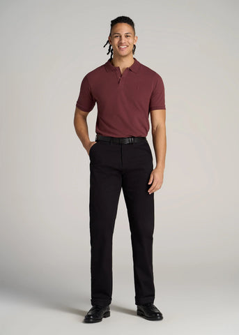 Man standing wearing tall classic polo with embroidered logo and dark pants