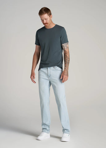 Man standing wearing essential slim fit crewneck paired with light jeans