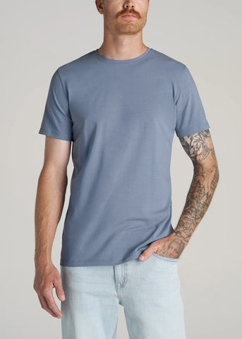 Closeup of man standing wearing essential men's slim-fit crewneck tall tee and light colored jeans