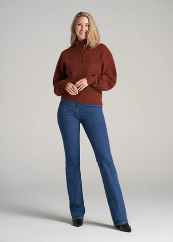 Tall woman standing up wearing button front mock neck sweater and bootcut blue jeans