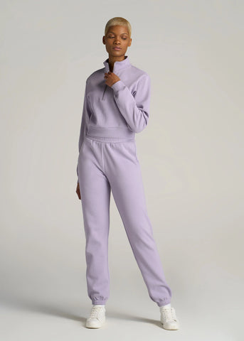 Tall woman standing wearing matching fleece sweatpants and cropped sweatshirt in pale purple
