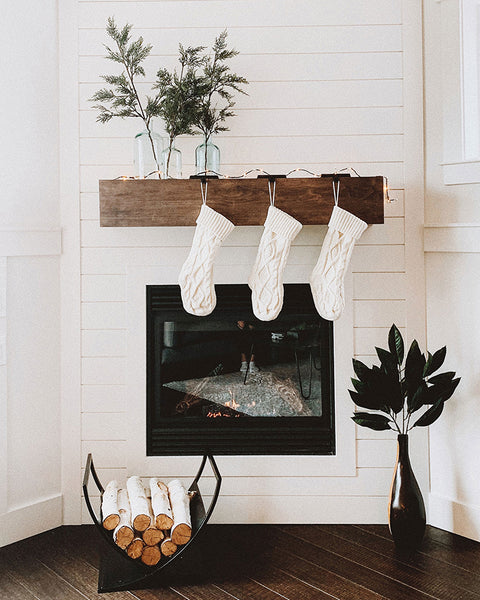 Christmas stockings on fireplace in cozy white room.