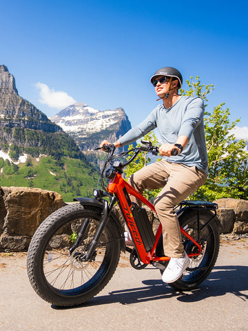 Young man riding a red Juiced Bikes RipCurrent S with mountains in the background