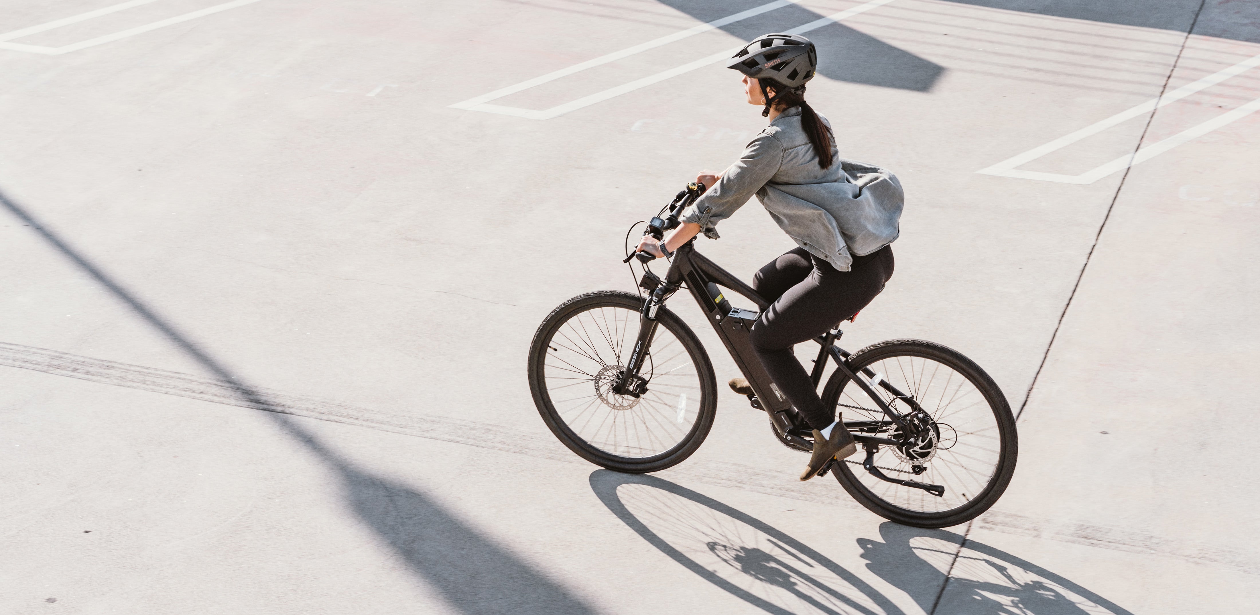 Woman Riding Black E-Bike in Parking Lot