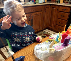 Toddler boy sitting at table, upset