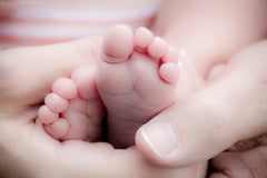 newborn baby feet held by adult hands