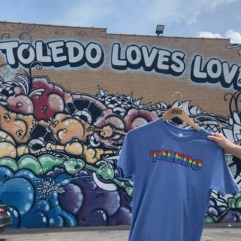 Toledo Rainbow shirt in front of Toledo Loves love Mural