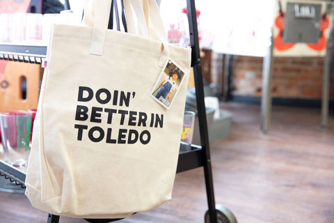 tote bag that has the words doin' better in toledo screen printed on it