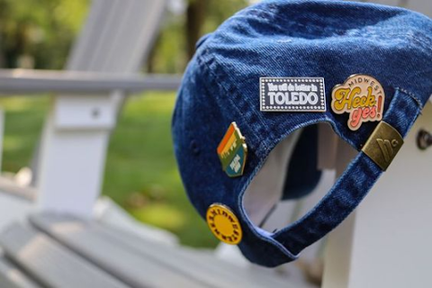 hat decorated with vintage enamel pins