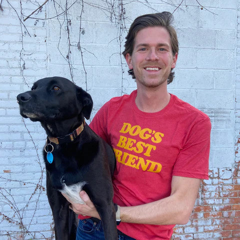 man wearing a dog’s best friend shirt while holding a dog