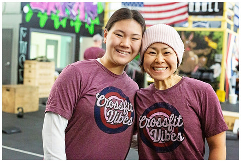 two women smiling in a crossfit gym while wearing matching shirts that say crossfit vibes