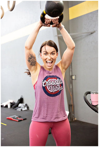 https://cdn.shopify.com/s/files/1/1010/8058/files/woman_smiling_and_holding_a_kettlebell_over_her_head_while_wearing_a_shirt_that_says_crossfit_vibes_480x480.jpg?v=1614872339