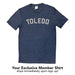 Your Exclusive Member Shirt ships immediately upon sign up! Heather Navy short sleeved shirt with "Toledo" in all caps, arched, in cream ink across center chest.