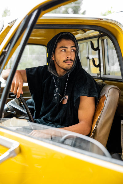 Marcus Paladino in vintage yellow truck while wearing a sustainable surf poncho
