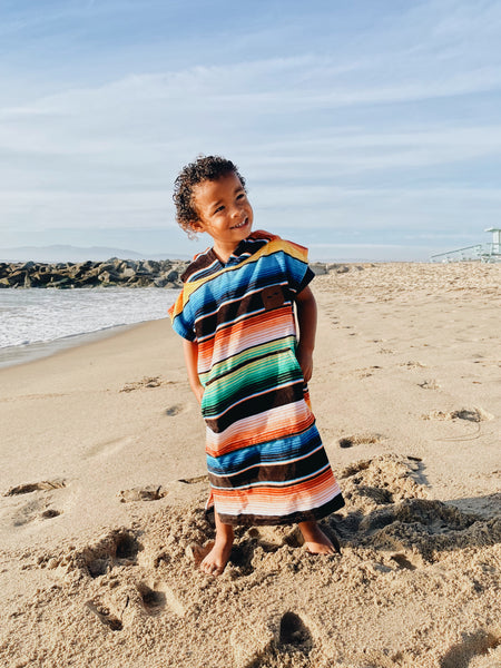 Toddler wearing sustainable swim poncho at the beach