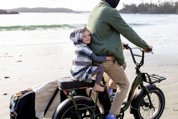 Father Daughter bike ride along the beach in sustainable surf poncho