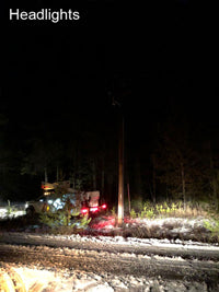 Overhead utility pole work lit by truck headlights