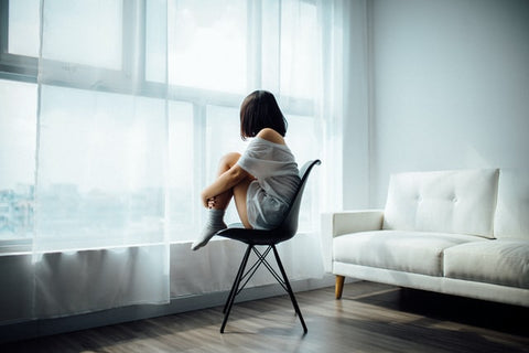 Girl sitting on the chair and looking through window