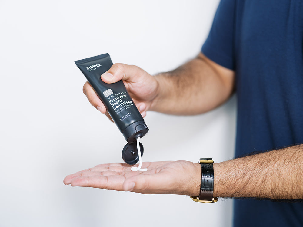 man squeezing beard conditioner into hand