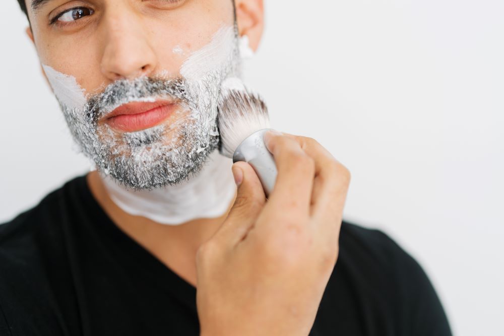 man applying ultra lather shaving cream with shave brush