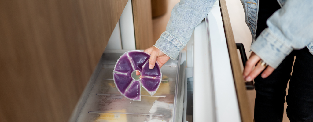 woman putting hot + cold breast pad in freezer