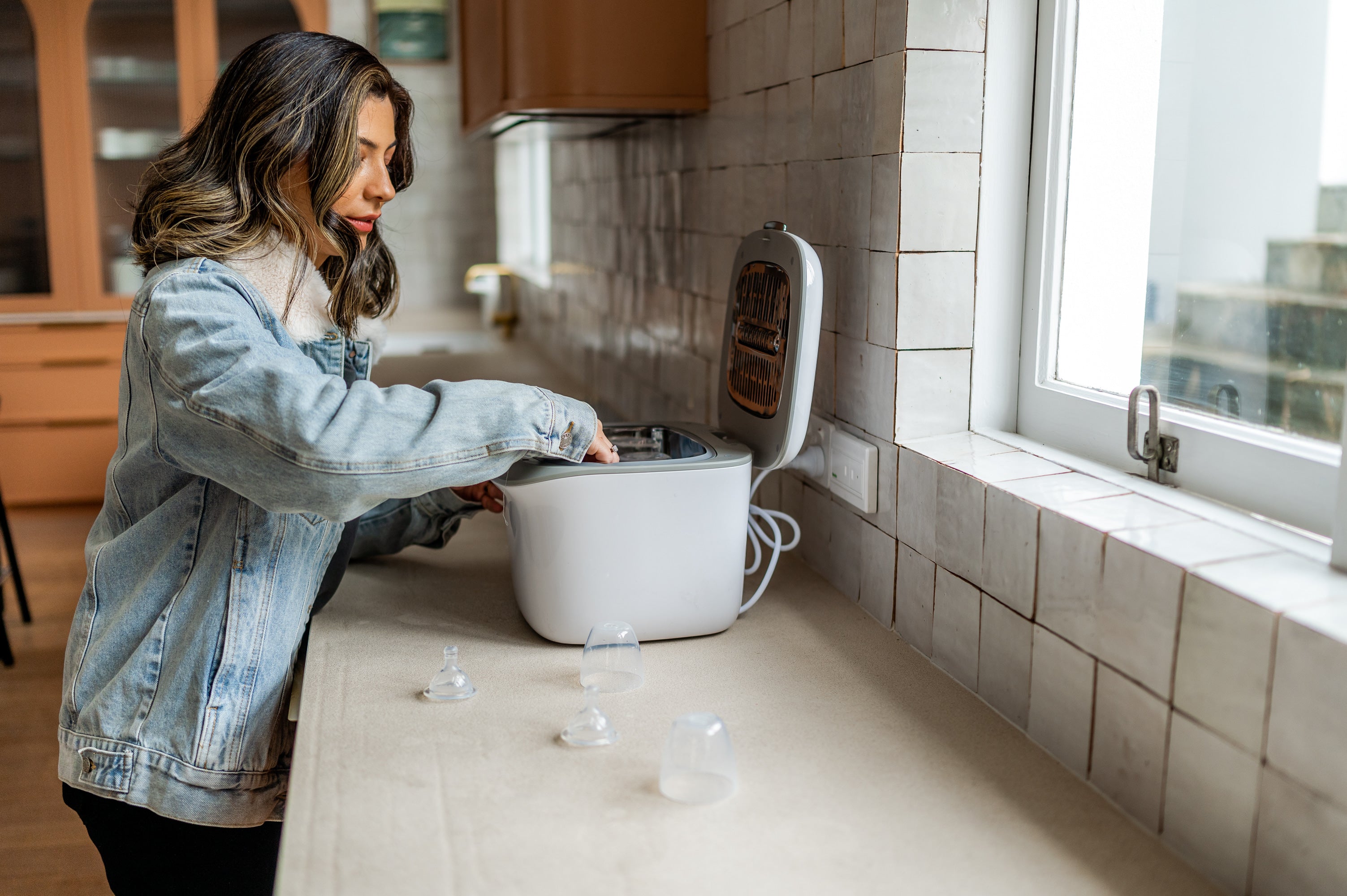 mother using baby bottle uv steriliser in kitchen