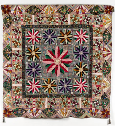 an ornate quilt made in 1887 from velvets with log cabin flowers and embroidered fans to the edges