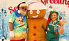 Santa Claus, in a beach-ready summer outfit, posing with GB Spice and a Rent-A-Christmas Elf at Christmas Con CA 2022 in Pasadena, California.
