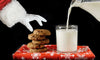 Santa Claus reaching for a chocolate chip cookie next to a glass of fresh milk