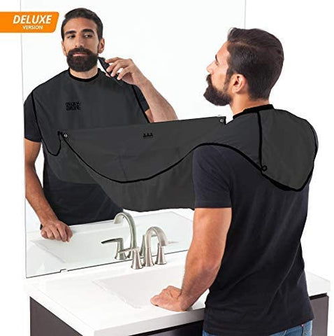 Man trimming beard, bathroom sink, faucet, black cape, mirror