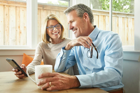 old man and woman, woman holding a phone, grey haired man, man holding a mug, man holding an eyeglass