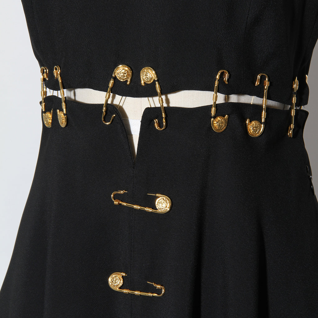 black versace dress with gold safety pins