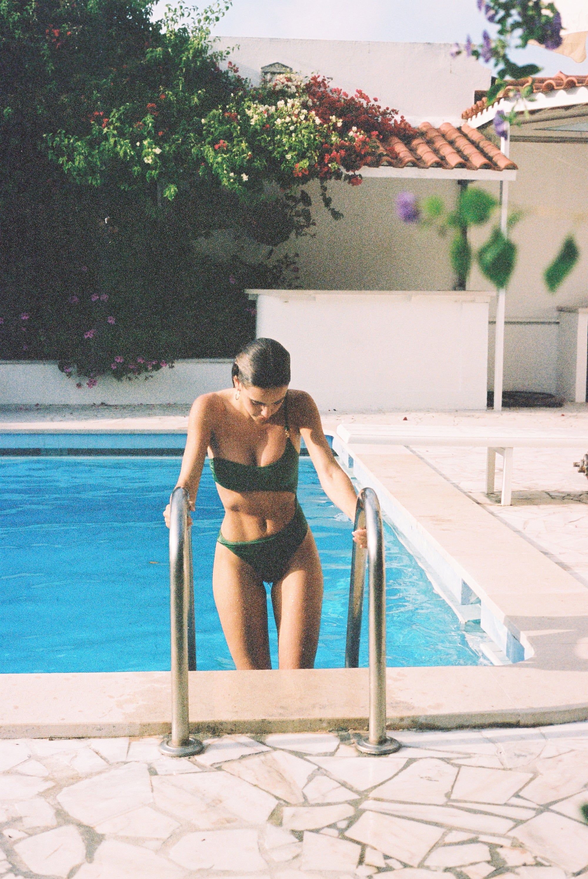 A Sommer Swim model getting out of the pool wearing a mint green cut-out one-piece bathing suit