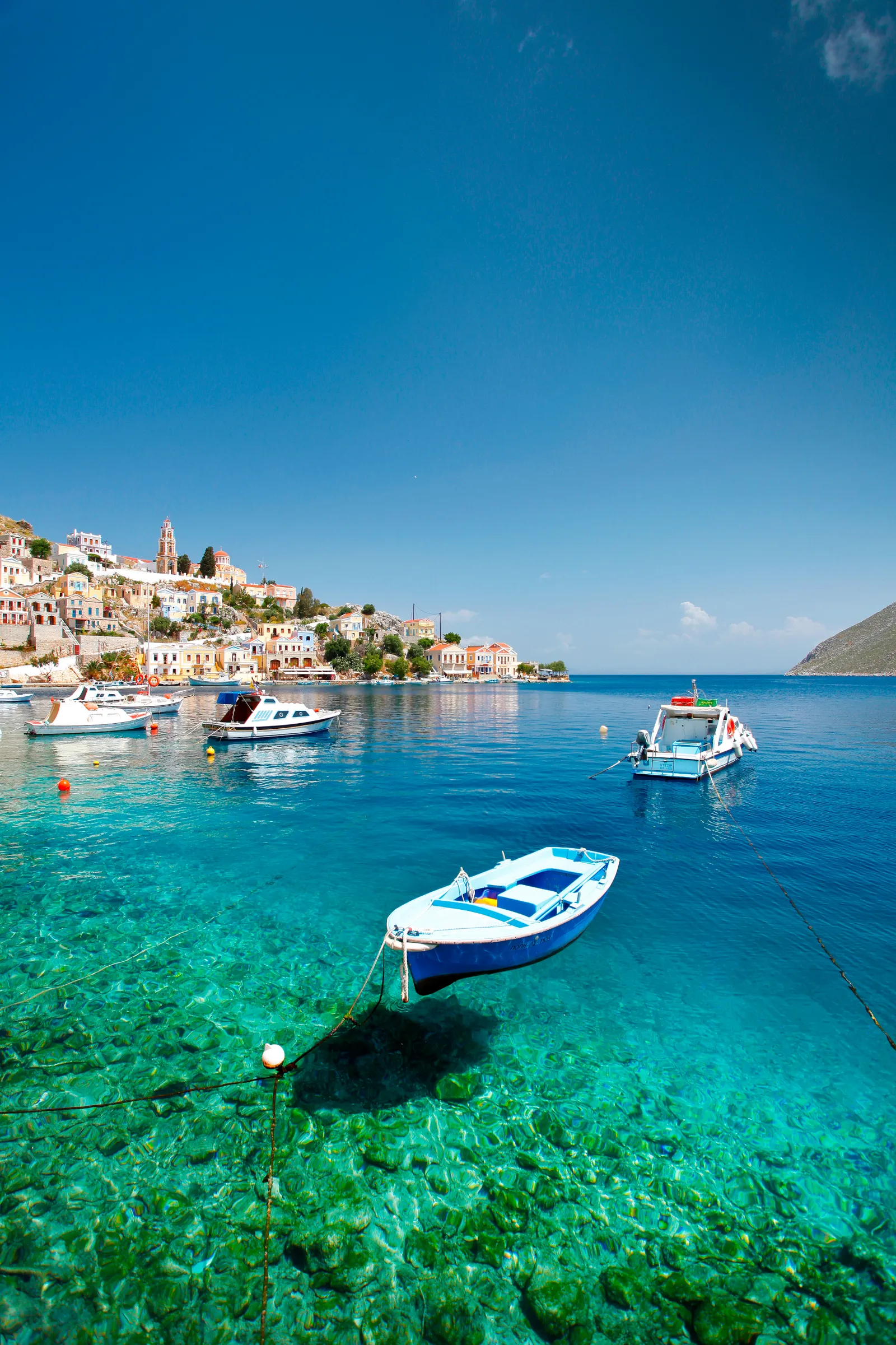 Crystal-clear green, turquoise, and blue waters in Saint George Bay in Symi, a small island in the Dodecanese