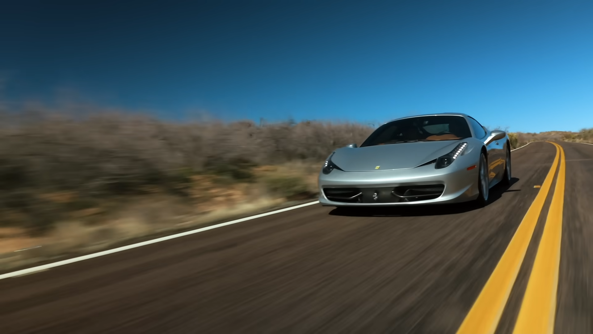Ferrari 458 argentée descendant l'autoroute dans le désert