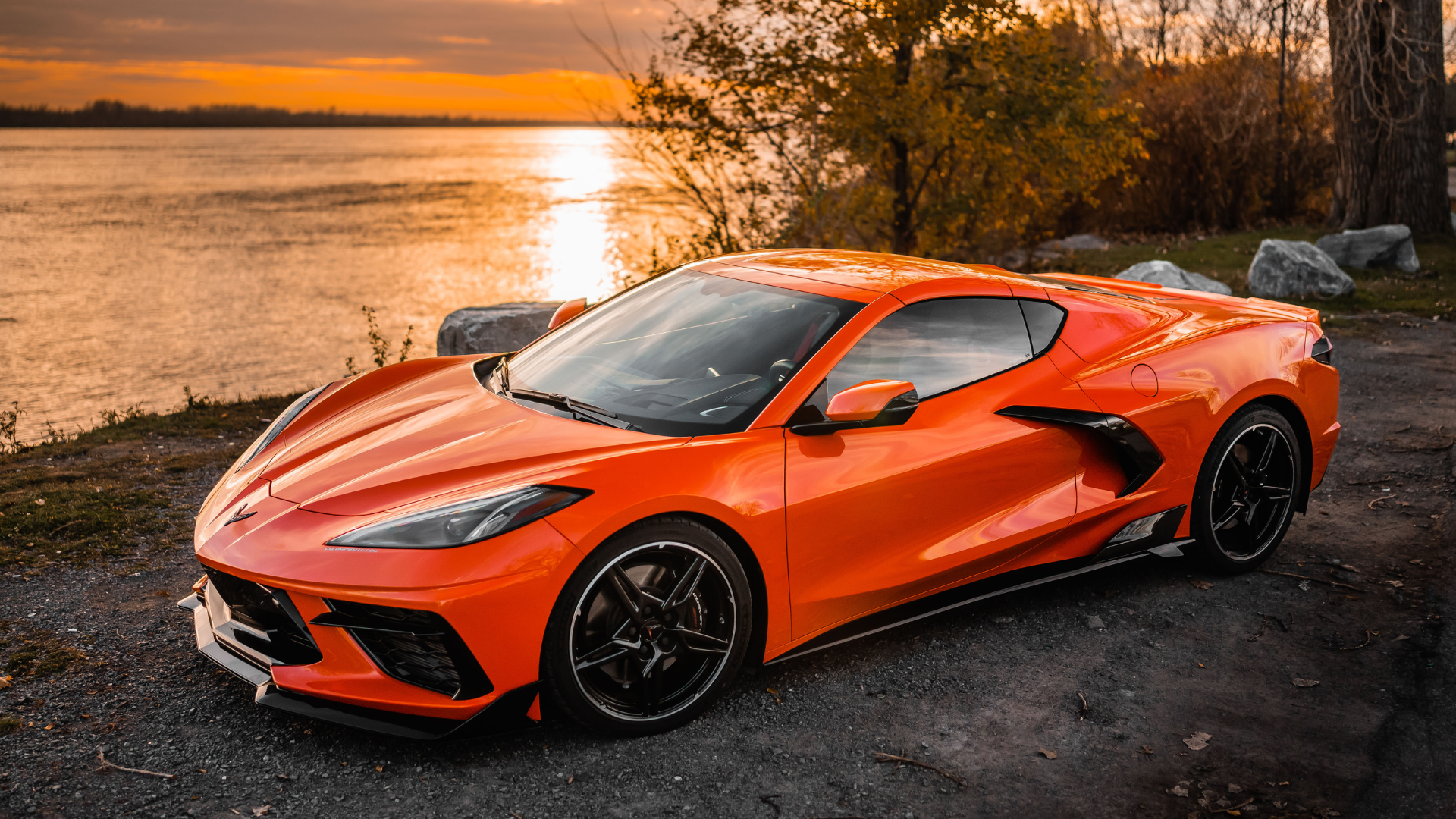 A Sebring Orange C8 Corvette in front of a sunset